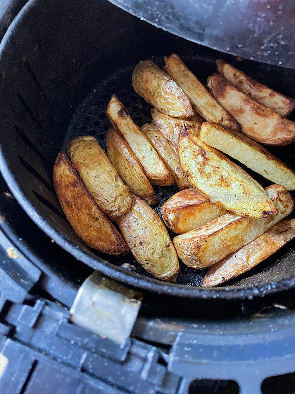 在空气炸锅里炸出的金黄色、新鲜酥脆的薯条/大块薯条，是零食烹饪的更健康的选择，从高处俯瞰